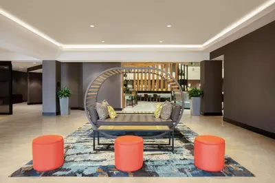 a lobby with a couch and orange stools at Embassy Suites by Hilton Orlando Airport in Orlando