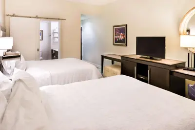 a hotel room with two beds and a flat screen tv at Hampton Inn & Suites Orlando-East UCF in Orlando