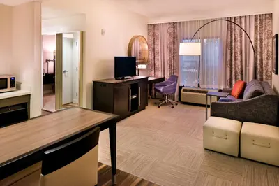 a hotel room with a desk and a living room at Hampton Inn & Suites Orlando-East UCF in Orlando