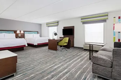 a hotel room with two beds and a couch at Hampton Inn & Suites Orlando International Drive North in Orlando