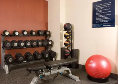 a gym with a bench and a bunch of weights at Hampton Inn Orlando Near Universal Blv/International Dr in Orlando