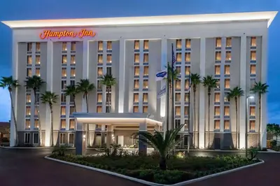 a hotel with palm trees in front of a building at Hampton Inn Orlando Near Universal Blv/International Dr in Orlando