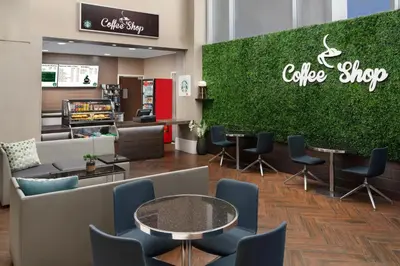 a cafe with chairs and tables and a green wall at Embassy Suites by Hilton Orlando Lake Buena Vista Resort in Orlando
