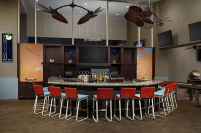 a bar in a room with red chairs at Embassy Suites by Hilton Orlando Lake Buena Vista Resort in Orlando