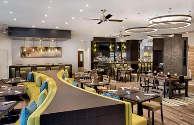 a restaurant with tables and chairs and a bar at Embassy Suites by Hilton Orlando International Drive Convention Center in Orlando