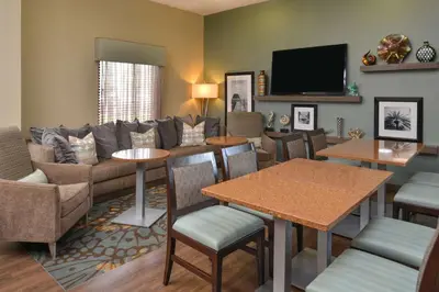 a living room with a couch and tables and a tv at Hampton Inn Closest to Universal Orlando in Orlando