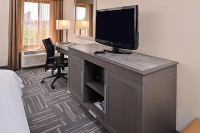 a hotel room with a desk with a television on it at Hampton Inn Closest to Universal Orlando in Orlando