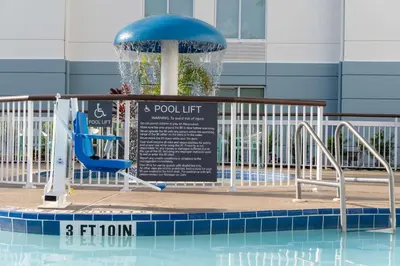 a pool with a chair and a water fountain at Hilton Garden Inn Orlando Airport in Orlando