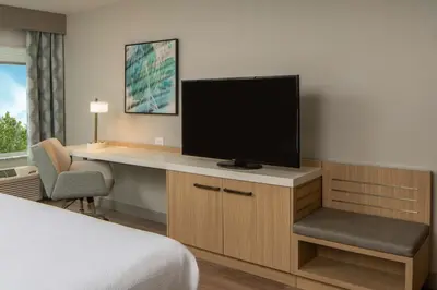a hotel room with a desk with a flat screen tv at Hilton Garden Inn Orlando Airport in Orlando