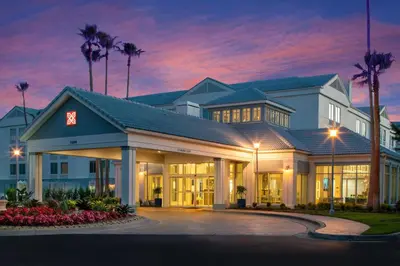 a hotel with palm trees in front of a building at Hilton Garden Inn Orlando Airport in Orlando