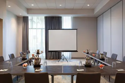 a conference room with a large screen in front of a table at Residence Inn by Marriott Orlando at Millenia in Orlando
