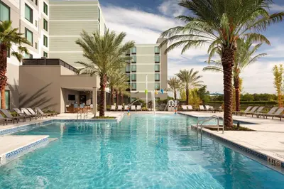 a swimming pool with palm trees in front of a building at SpringHill Suites by Marriott Orlando at Millenia in Orlando