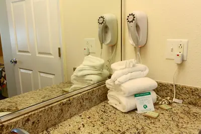 a pile of towels on a counter in front of a mirror at Orlando Inn International Drive Area in Orlando