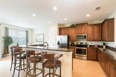a kitchen with wooden cabinets and a island with bar stools at Luxury Dreams Disney Home with Private Pool and Spa in Orlando