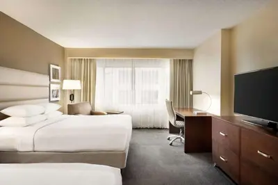 a hotel room with two beds and a desk and a television at DoubleTree by Hilton Orlando Downtown in Orlando