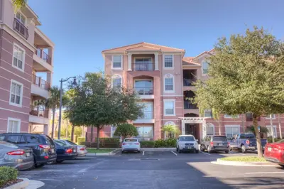 a parking lot with cars parked in front of a building at Beautiful PET FRIENDLY Condo Near Pool in Orlando