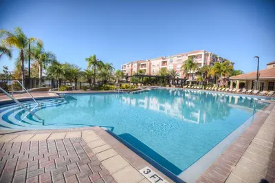 a large swimming pool with palm trees and buildings at Beautiful PET FRIENDLY Condo Near Pool in Orlando
