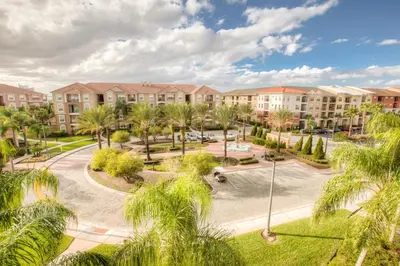 an apartment complex with a courtyard with palm trees at Stunning Top-Floor Condo, next to Clubhouse in Orlando