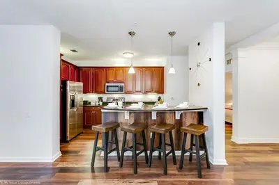 a kitchen with wooden cabinets and a bar with stools at Newly Renovated 1st-Floor Condo at Vista Cay in Orlando
