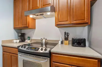 a kitchen with wooden cabinets and a stove top oven at Cozy Condo w FREE Vista Cay Resort Access in Orlando