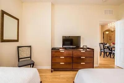 a bedroom with a dresser with a television and a chair at Luxurious Condo w Modern Design, near Disney in Orlando