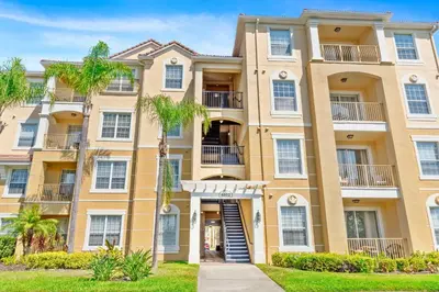 a large apartment building with palm trees in front of it at Modern Vista Cay Condo, near Universal Studios in Orlando