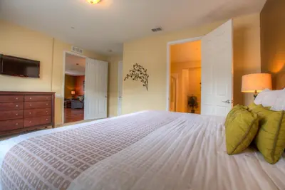 a bedroom with a large white bed with a television at Stylish Condo at Vista Cay Resort Minutes to WDW in Orlando
