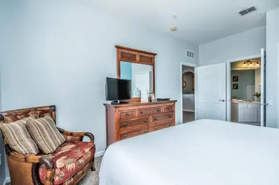 a bedroom with a bed and a chair and a television at Majestic Holiday in Orlando