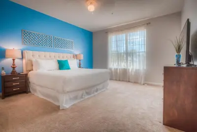 a bedroom with a white bed and a blue wall at Beautiful LAKEVIEW Deluxe Condo Near Theme Parks in Orlando