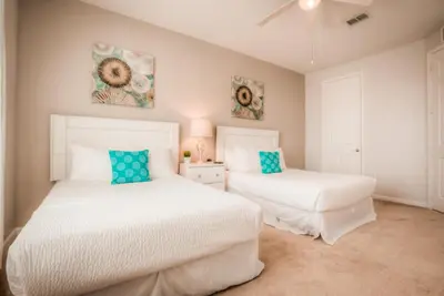 two beds in a bedroom with white sheets and blue pillows at Beautiful LAKEVIEW Deluxe Condo Near Theme Parks in Orlando