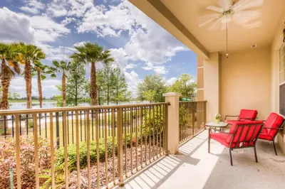 a balcony with two red chairs and a table and palm trees at Newly Renovated LAKEVIEW Vista Cay Condo in Orlando