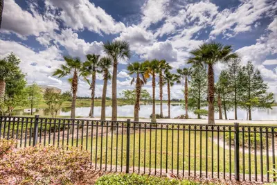 a fence with palm trees in front of a lake at Newly Renovated LAKEVIEW Vista Cay Condo in Orlando
