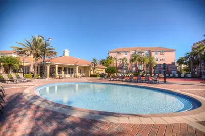 a swimming pool with chairs and a house in the background at Luxurious Condo wPrivate Balcony AMAZING View in Orlando