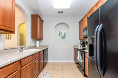 a kitchen with a black refrigerator and wooden cabinets at Gorgeous Vista Cay Condo, next to Resort Clubhouse in Orlando
