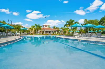 a swimming pool at a resort with blue umbrellas at Spacious Condo in Vista Cay Resort LUXURY AWAITS in Orlando