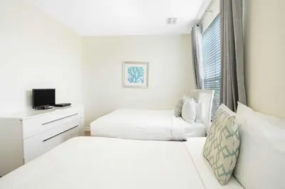 a white bedroom with two beds and a window at 3-Story Townhome at Vista Cay Resort in Orlando