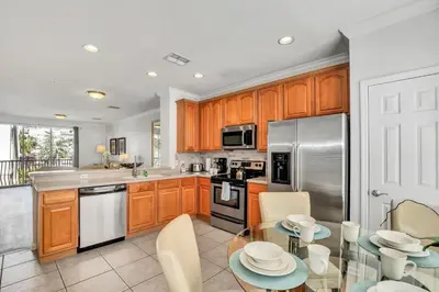 a kitchen with wooden cabinets and a glass table at NEWLY RENOVATED Townhome, Near Universal & I-Drive in Orlando