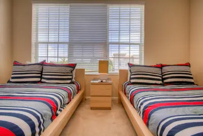 two beds in a room with two windows at Resort Townhome: Perfect Orlando Vacation Spot in Orlando