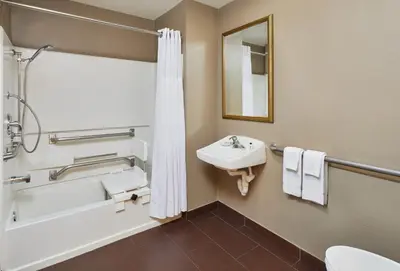 a bathroom with a sink and a tub and a toilet at Staybridge Suites Orlando South by IHG in Orlando