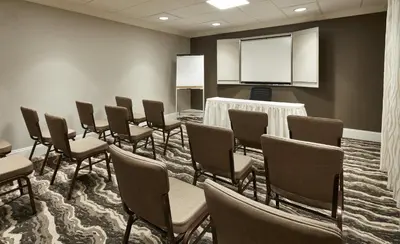 a conference room with chairs and a screen at Staybridge Suites Orlando South by IHG in Orlando