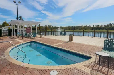 a swimming pool with chairs and a table at SPECTACULAR Home And Resort! Near Dis, Splash Park, Lake With Boats, Pool, This Home And Resort Has It ALL! Low Rates Too! in Kissimmee