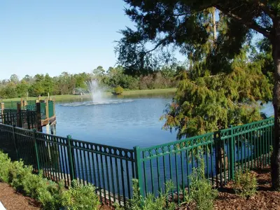a fence around a lake with a fountain at SPECTACULAR Home And Resort! Near Dis, Splash Park, Lake With Boats, Pool, This Home And Resort Has It ALL! Low Rates Too! in Kissimmee