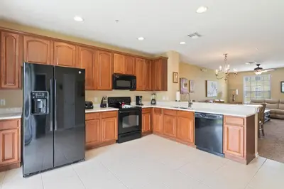a kitchen with wooden cabinets and a black refrigerator at Orlando Resort Rentals at Universal Boulevard in Orlando