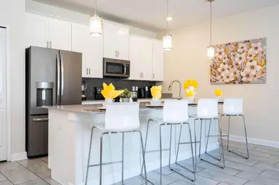 a kitchen with white cabinets and a kitchen island with white stools at Family Friendly Four Bedrooms w/ Pool 4896 in Kissimmee