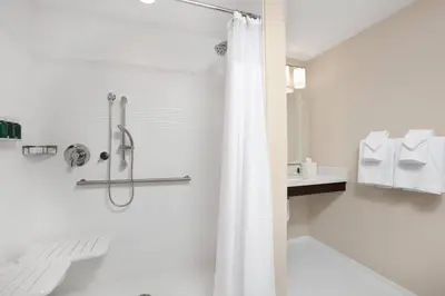 a white bathroom with a shower and a sink at TownePlace Suites by Marriott Orlando Theme Parks Lake Buena Vista in Orlando