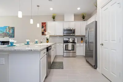 a kitchen with white cabinets and stainless steel appliances at Four Bedroom w/ GameRoom 5152A in Kissimmee