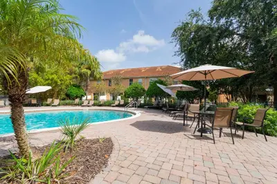a patio with tables and umbrellas next to a pool at Family Friendly Four Bedrooms 5147A in Kissimmee