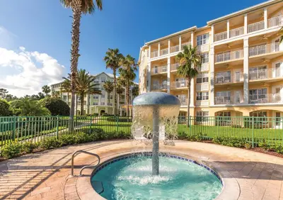 a fountain in front of a building with palm trees at WorldMark Orlando Kingstown Reef in Orlando