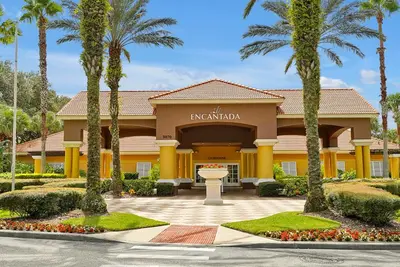 a hotel with palm trees in front of a building at Encantada Resort Vacation Townhomes by IDILIQ in Kissimmee