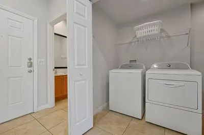 a laundry room with two washing machines and a door at Encantada Resort Vacation Townhomes by IDILIQ in Kissimmee